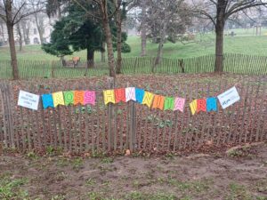 Une banderole colorée "Cross humanitaire" est affichée sur une palissade dans un parc